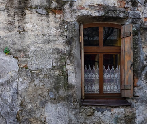 solid wood window frame with dark varnish on the side of an aged rustic building